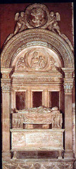 14. Bernardo Rossellino, Tomb of Leonardo Bruni, 1450, CE, Santa Croce, Florence, Italy, marble. Considered his greatest masterpiece, Rossellino combines both architecture and sculpture into one marble tomb. The tomb was commissioned by Leonardo Bruni himself, a Florentine chancellor, who died in 1944. He commissioned this elaborate tomb to elevate his status to more than just a chancellor after his death. The format of the tomb recalls that of a triumphal arch and within the tympanum is a relief of the Madonna. Viewers are reminded of his legacy by Bruni's coat of arms perched on the arch surrounded by two cherubs.